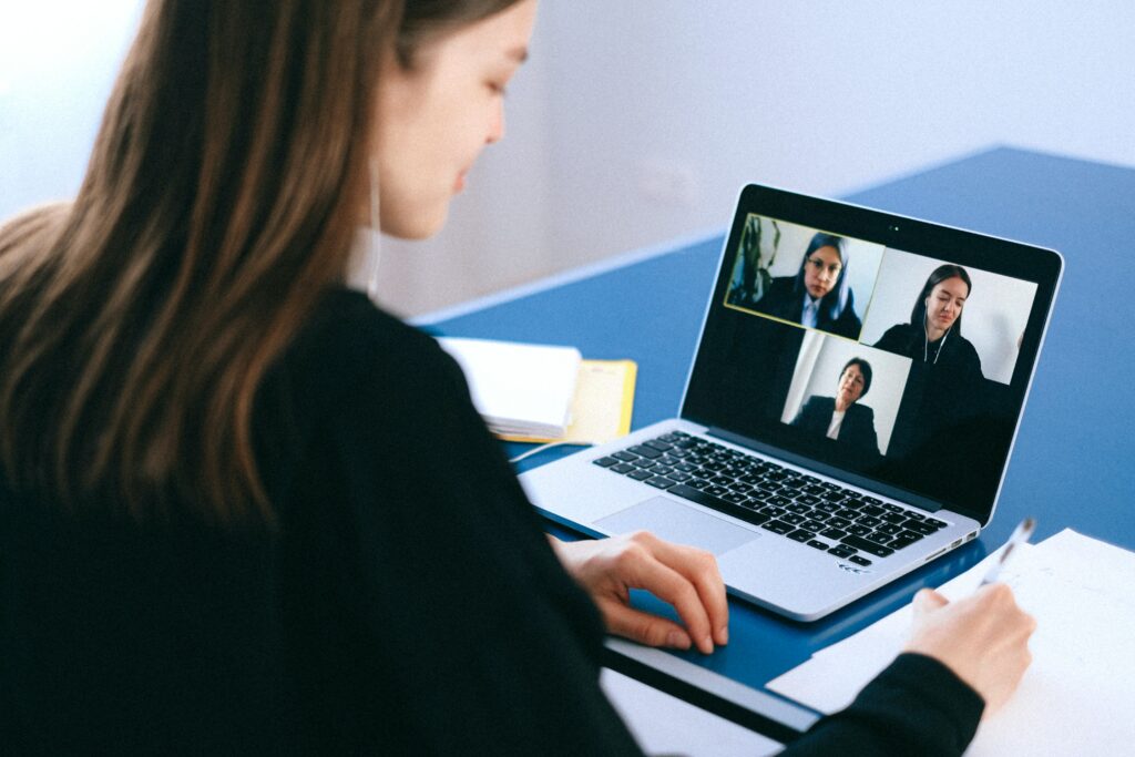 Woman having video meeting with 3 individuals on the screen